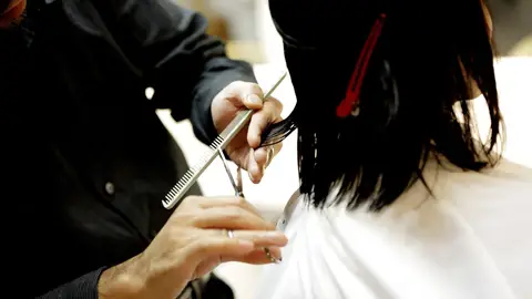 Una mujer cortándose el pelo Una mujer cortándose el pelo