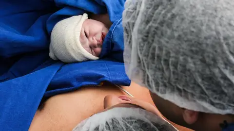 mujer en el paritorio con el recién nacido en sus brazos