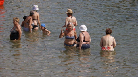 Un grup de persones banyant-se a la platja en plena onada de calor al 2018.