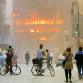 Gente en la calle observando uno de los edificios en llamas tras el ataque terrorista del 11S