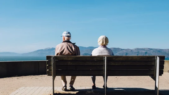 Dos ancianos sentados en un banco mirando hacia el horizonte costero Dos ancianos sentados en un banco mirando hacia el horizonte costero