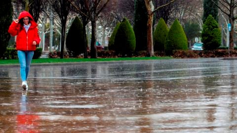 Una mujer se protege de la lluvia, en una fotograf&iacute;a de archivo