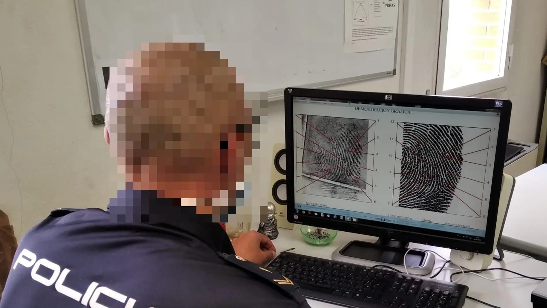 Agente de la Policía Nacional de Elche visiona el estudio de la huella dactilar encontrada en la pistola.