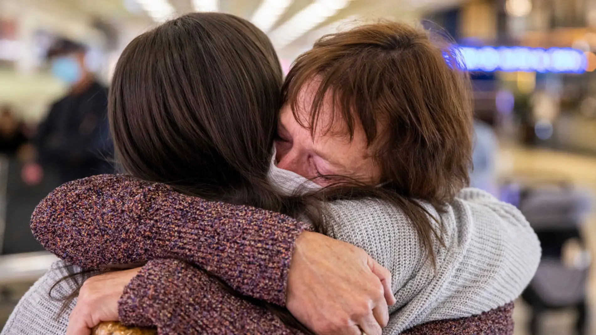 Una madre y una hija se abrazan en la terminal de un aeropuerto