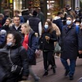Varias personas en una calle céntrica de Ámsterdam llevando mascarillas por la pandemia de coronavirus