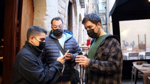 Unos clientes validan el certificado covid antes de entrar en un restaurante.