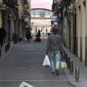 Un hombre transita con bolsas de la compra por la madrileña calle La Ruda, en una imagen de archivo.
