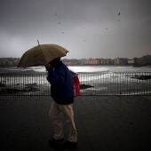 Un hombre se protege de la lluvia en el paseo marítimo de A Coruña, en una imagen de archivo. 