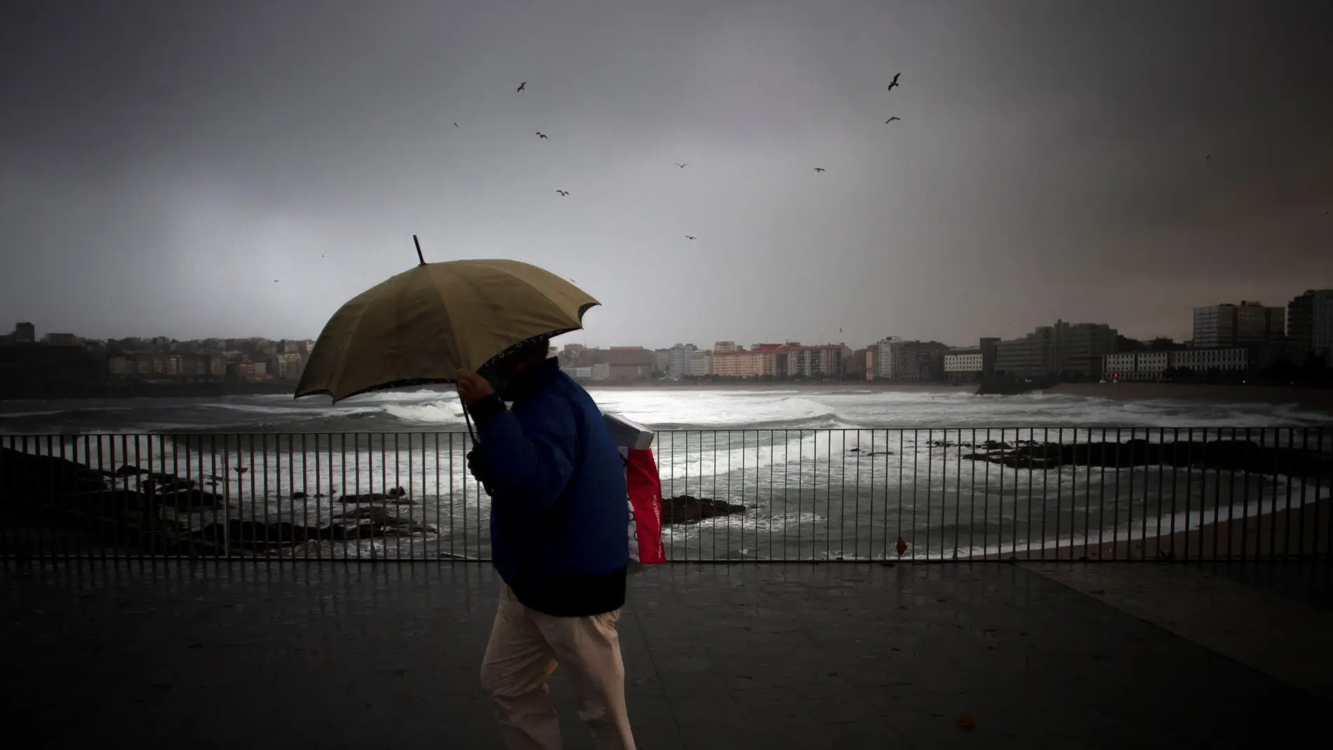 Un hombre se protege de la lluvia en el paseo marítimo de A Coruña, en una imagen de archivo. 