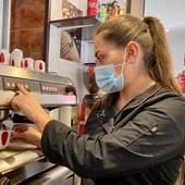 Una mujer preparando un café en un bar. Una mujer preparando un café en un bar.