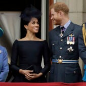Meghan Markle y el príncipe Harry, sonrientes tras la reina Isabel II en una imagen de 2018