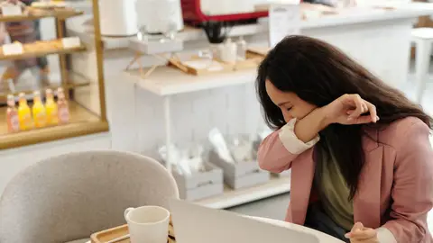 Una mujer estornudando en el trabajo