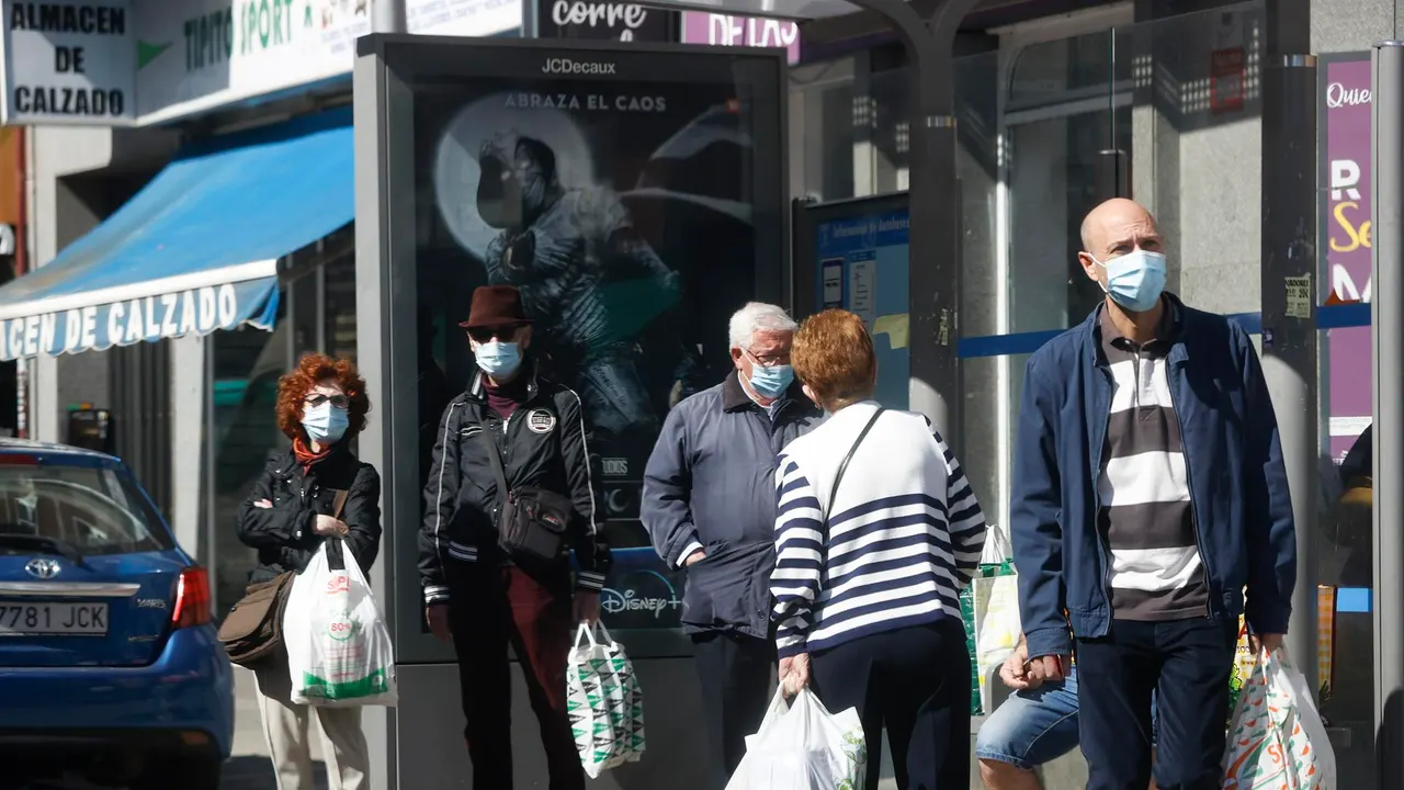 Varias personas con mascarilla esperan el autobús.