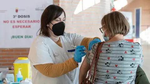 Una enfermera administra la tercera dosis de la vacuna Covid a una mujer.