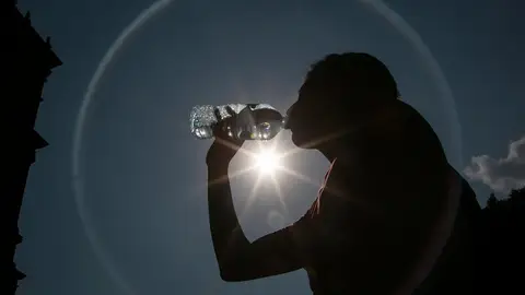 Una mujer bebe agua para hacer frente al calor