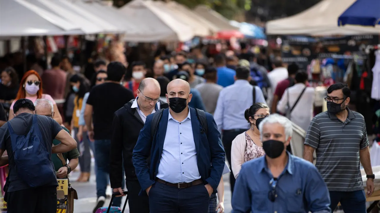 Varias personas caminan por la calle con mascarilla.
