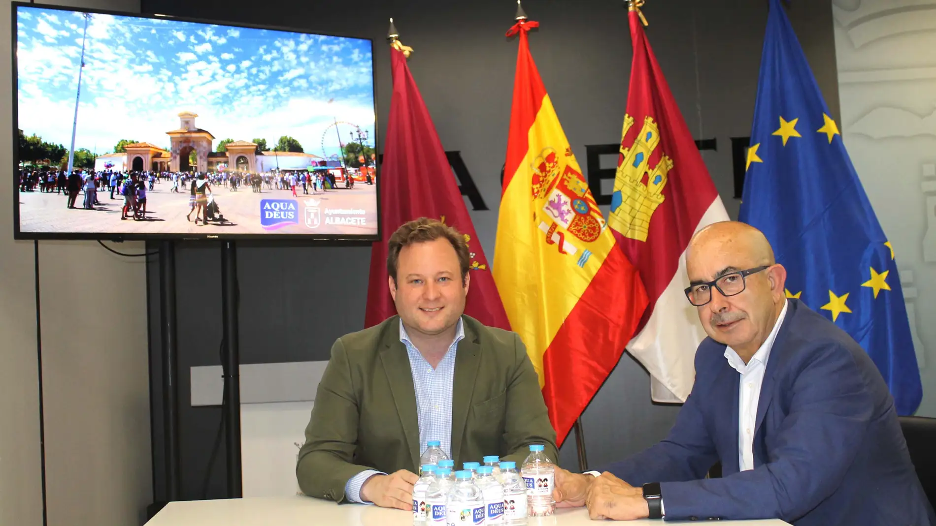 El director comercial de Aquadeus, Julián Garre (derecha) y el primer teniente alcalde de Albacete, Vicente Casañ (izquierda), durante la presentación de la edición especial de los botellines de Aquadeus con los motivos de la Feria de Albacete.