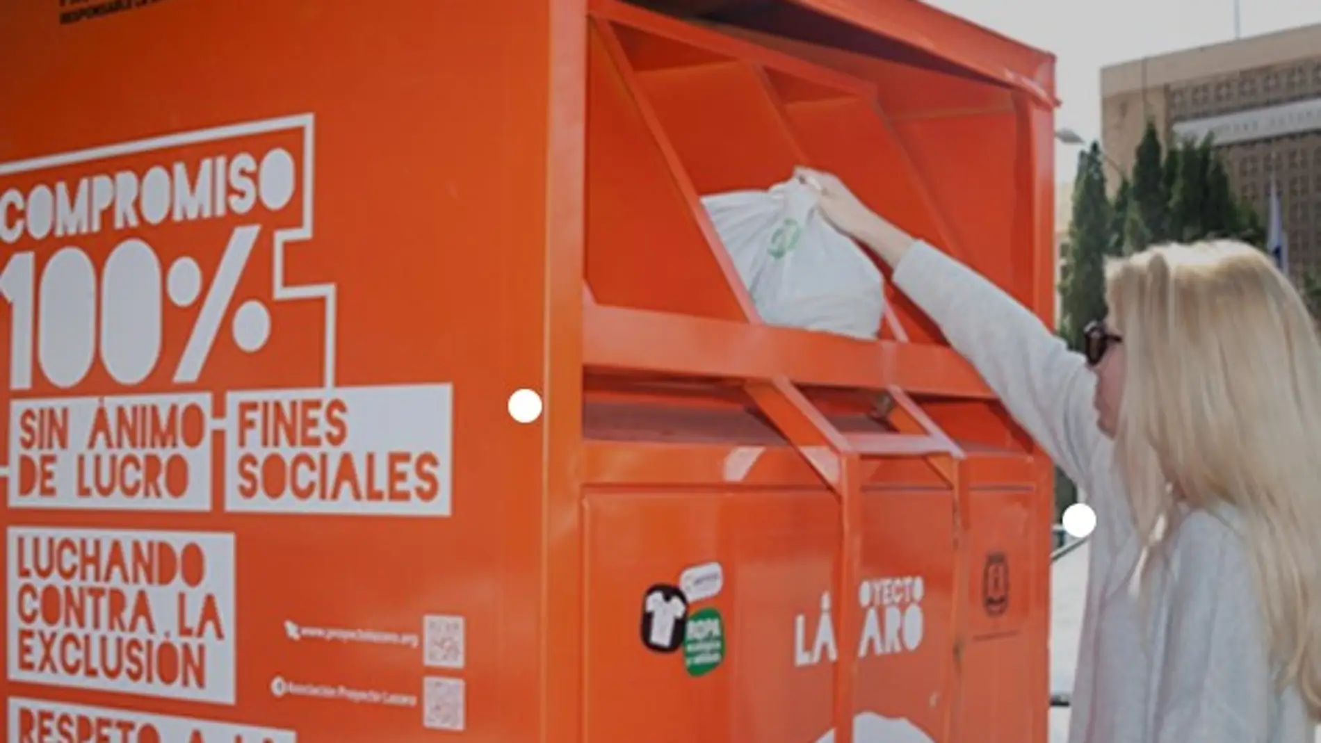 Una mujer deposita una bolsa de ropa en un contendedor de Proyecto Lázaro