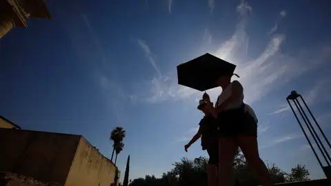 Dos personas pasean con un paraguas por las altas temperaturas.