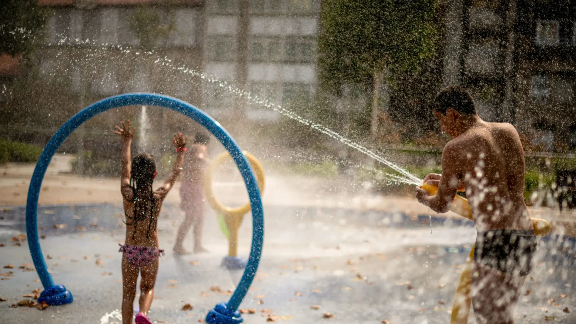 Un padre juega con su hija en una fuente pública debido a la ola de calor