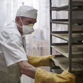 Un trabajador  maneja bandejas para cocer pan.