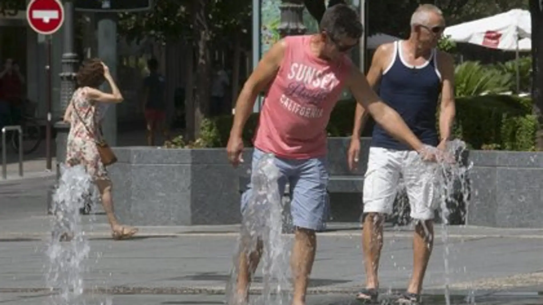Personas refrescándose en una fuente debido a las altas temperaturas.