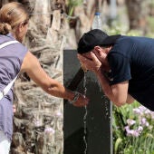 Dos personas se refrescan en una fuente de Valencia durante la ola de calor