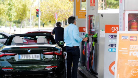 Unas personas repostan combustible en una gasolinera de Madrid