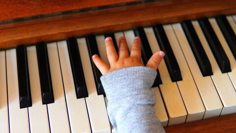 Imagen de la mano de un ni&ntilde;o sobre un piano