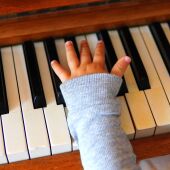 Imagen de la mano de un niño sobre un piano