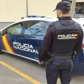 Un agente de la Policía Nacional en Palma junto al coche policial.
