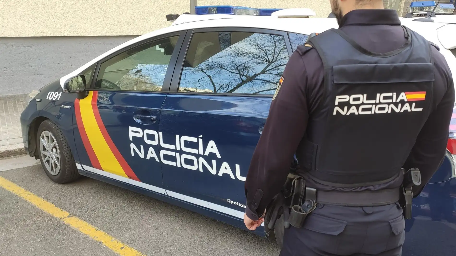 Un agente de la Policía Nacional en Palma junto al coche policial. Un agente de la Policía Nacional en Palma junto al coche policial.