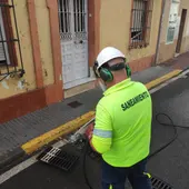 Uno de los trabajadores limpiando un imbornal Uno de los trabajadores limpiando un imbornal