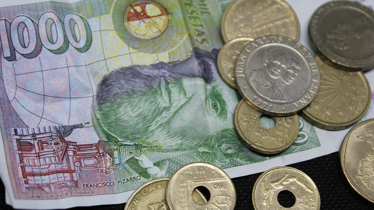 Una imagen de archivo con un billete y varias monedas de pesetas.