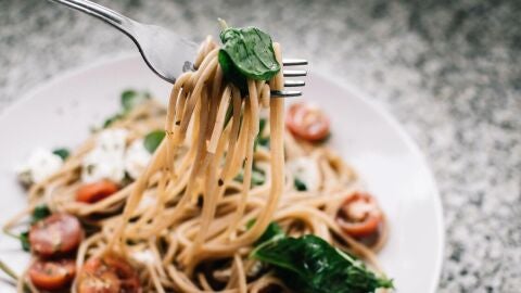 Una persona come un plato de pasta con un tenedor