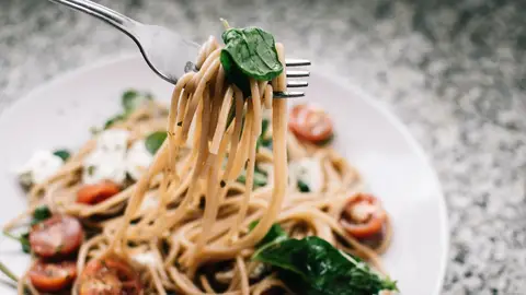 Una persona come un plato de pasta con un tenedor Una persona come un plato de pasta con un tenedor