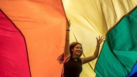 Una mujer camina bajo una bandera gigante del arco iris mientras participa en el Desfile del Orgullo Gay de Praga 