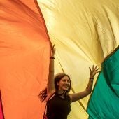 Una mujer camina bajo una bandera gigante del arco iris mientras participa en el Desfile del Orgullo Gay de Praga 