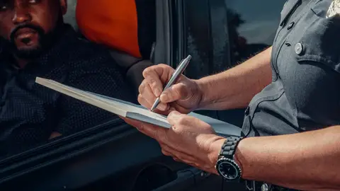 Un policía poniendo una multa Mesa de redacción: multas sin notificar
