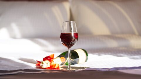 Copa de vino y botella de champagne en una cama