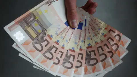 Una persona enseña varios billetes de 50 euros. Una persona enseña varios billetes de 50 euros.