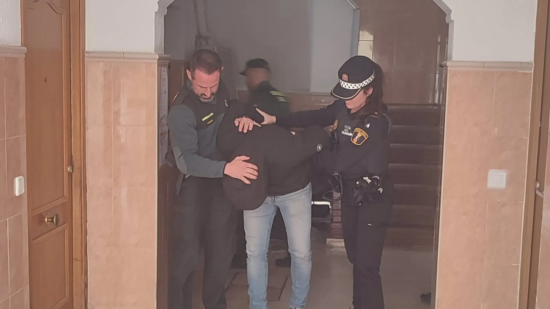 El joven detenido es sacado de la vivienda por los agentes