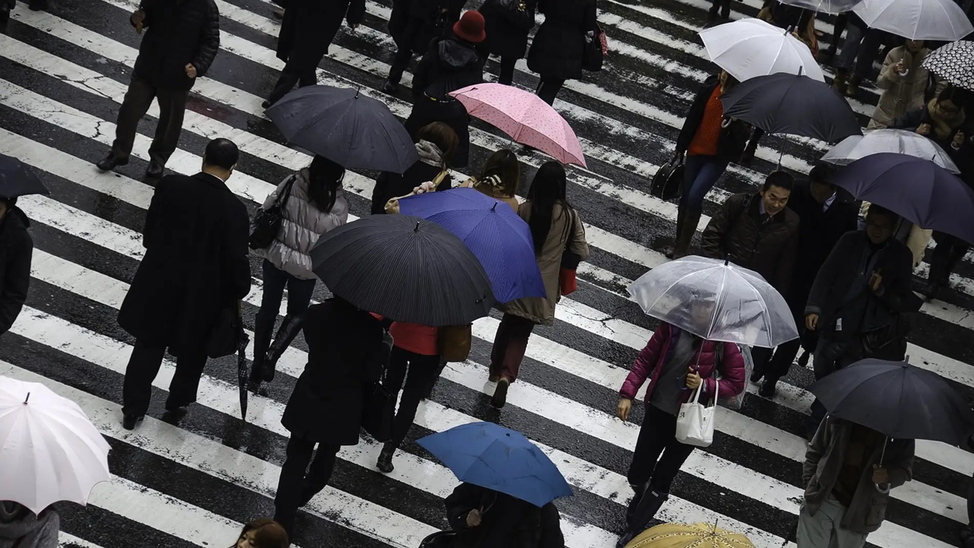 Imagen de archivo de varias personas andando por la calle bajo sus paraguas en un día lluvioso