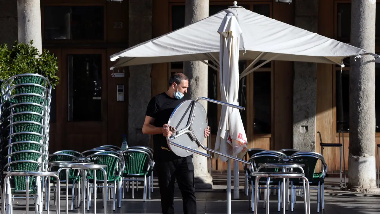 Imagen de archivo de un camarero colocando mesas en la terraza de un bar. Imagen de archivo de un camarero colocando mesas en la terraza de un bar.