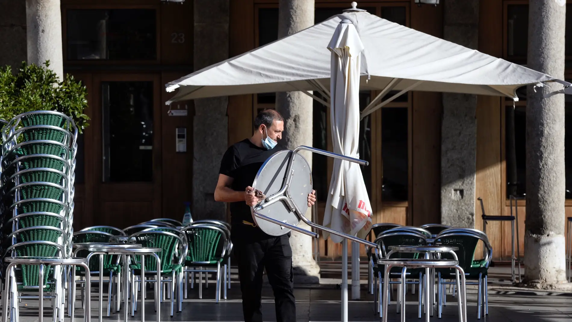 Imagen de archivo de un camarero colocando mesas en la terraza de un bar.