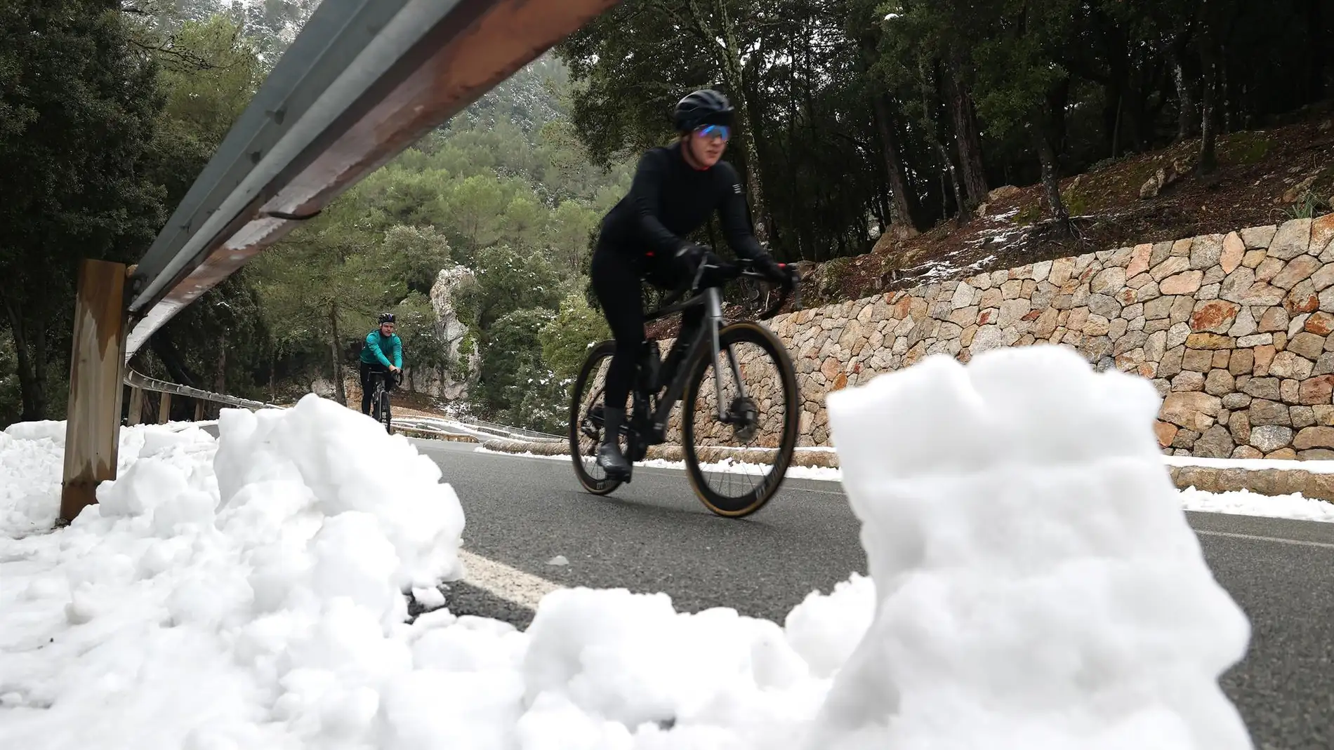 Unos ciclistas bajan una carretera en la Serra de Tramuntana a pesar de la nieve