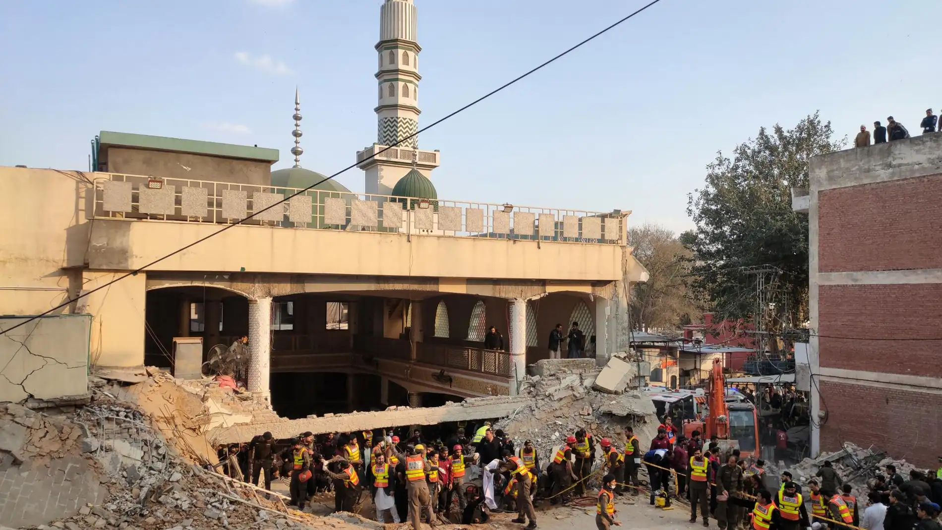 Trabajadores de los servicios de emergencia buscan posibles victimas entre los escombros de una mezquita de Peshawar tras un atentado suicida