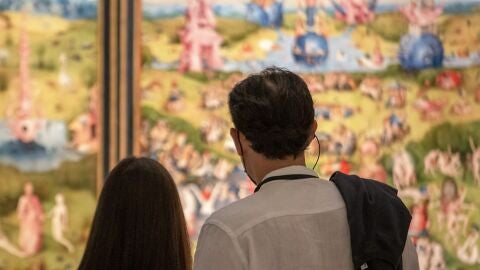 Dos personas contemplan en el Museo Nacional del Prado el cuadro cuadro &lsquo;El jard&iacute;n de las delicias&rsquo; del Bosco.