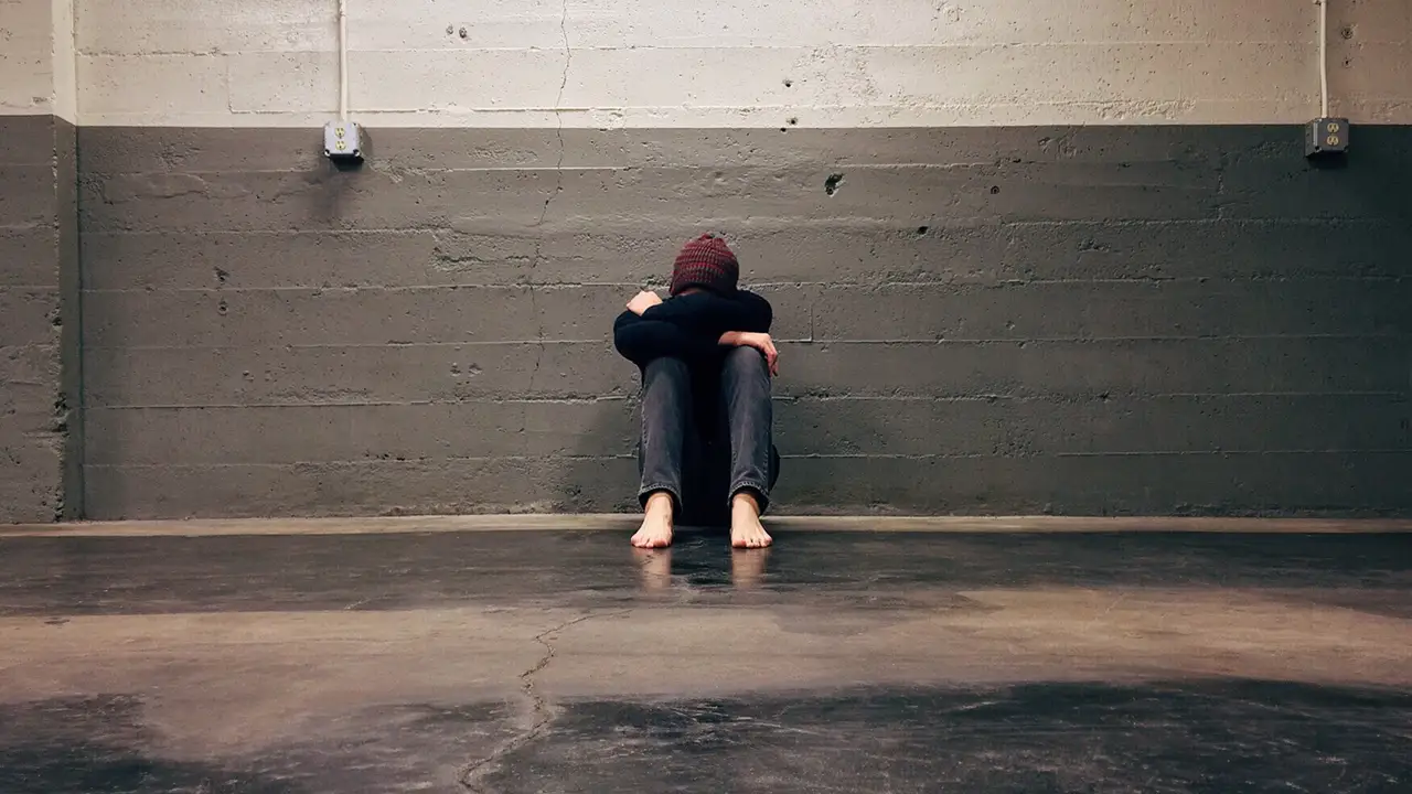 Persona con depresión sentada en un garaje Persona con depresión sentada en un garaje