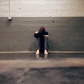 Persona con depresión sentada en un garaje Persona con depresión sentada en un garaje